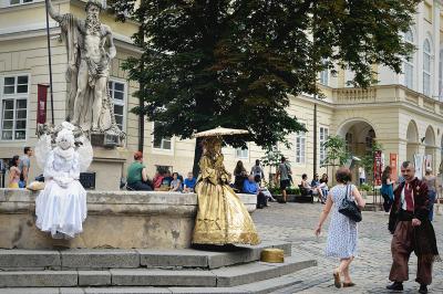 Живые скульптуры сидят на фонтане на площади Рынок